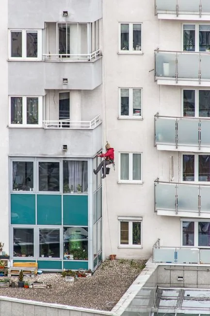 A man in a harness cleaning skyscraper windows with precision.